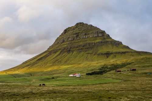 Free Scenic view of Kirkjufell mountain with rural houses and horses in Iceland. Stock Photo