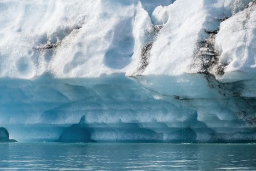 Free A detailed view of a melting iceberg edge showcasing stunning blue ice and dripping water, illustrating climate change effects. Stock Photo