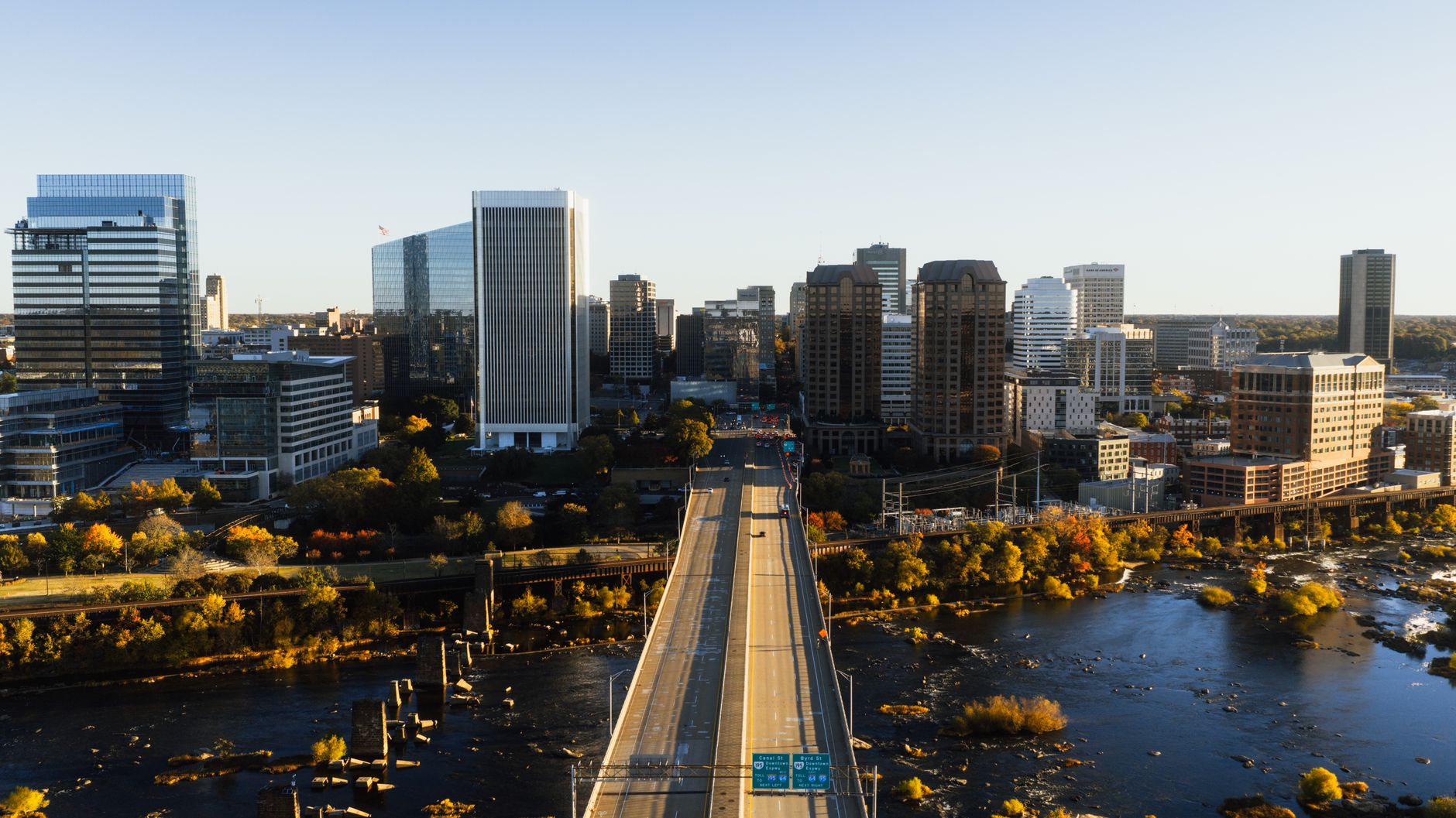 Aerial view of Richmond, Virginia skyline with bridge and river at dusk showcasing city architecture.