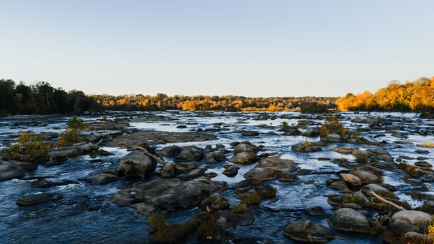 Beautiful fall scene at the James River with rocks and autumn foliage in Richmond, Virginia.