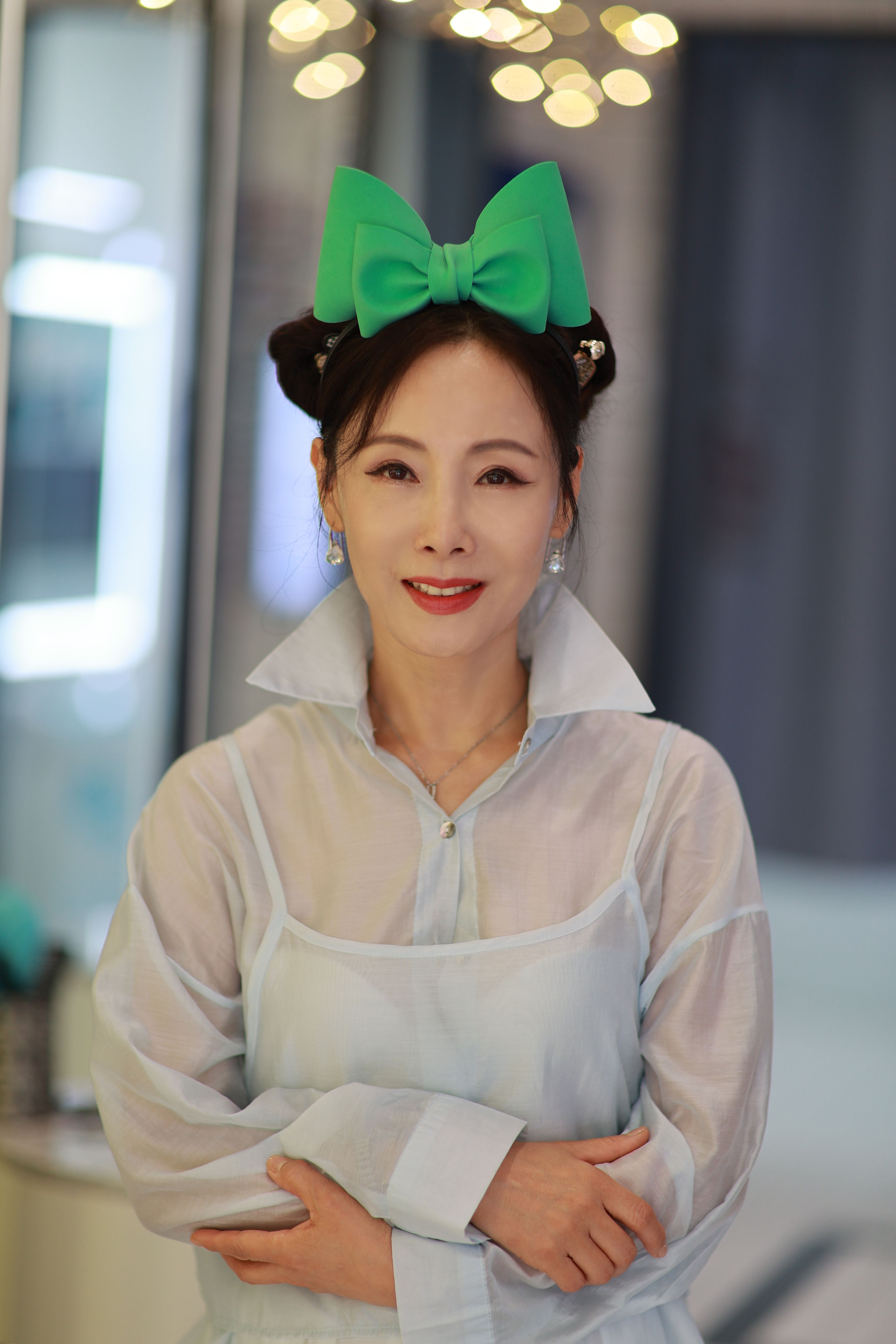 A stylish woman in Seoul wearing a green bow, captured indoors with a soft focus background.