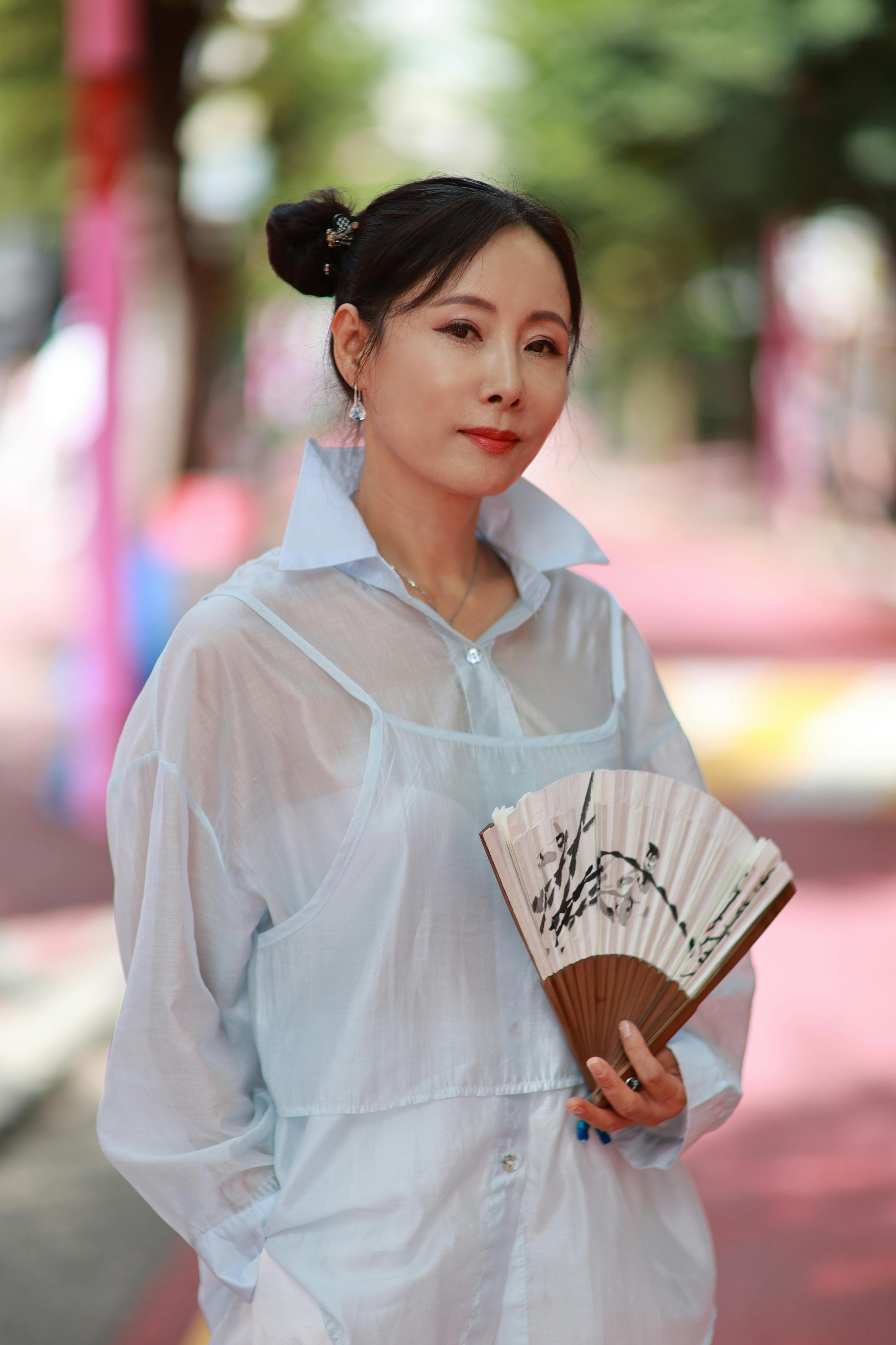 grátis Mulher elegante em Seul segurando um leque tradicional, demonstrando a cultura coreana. Foto profissional