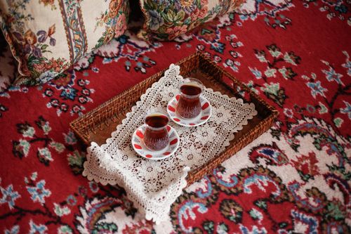 Free Two Turkish tea glasses on a lace tray atop an ornate red carpet, exuding warmth. Stock Photo