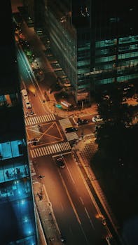 Aerial shot of a city intersection at night with glowing streetlights and light traffic.
