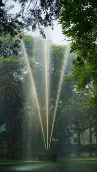 A majestic outdoor fountain sprays water in a lush park setting, surrounded by greenery.
