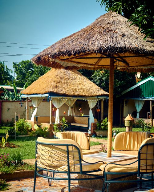 Free Captivating garden scene with thatch roofs and chairs, perfect for relaxation in Nigeria. Stock Photo
