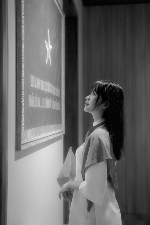 Free Woman in traditional attire gazing at a star artwork on a wall indoors. Stock Photo