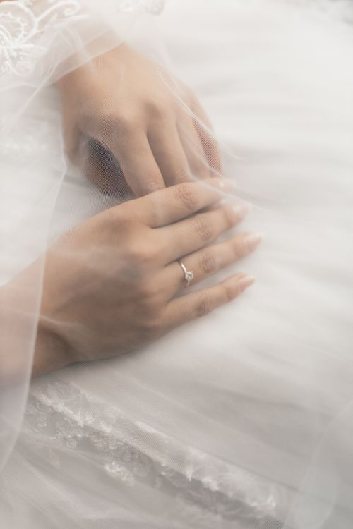 Free Close-up of a bride's hands with a diamond ring on a tulle gown, symbolizing elegance. Stock Photo