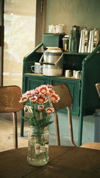 Charming café scene with flowers on table, vintage decor in background.