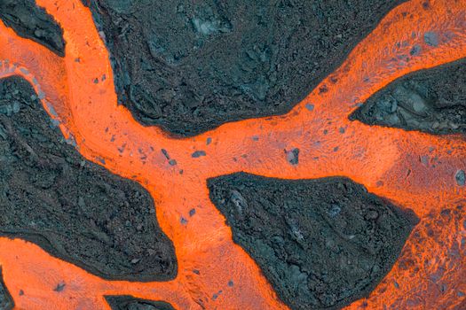 Stunning aerial photograph of bright orange lava flowing through dark volcanic rock in Iceland.