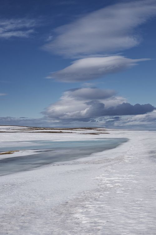 Free A serene Arctic scene showcasing snow and cloud formations under a clear blue sky. Stock Photo