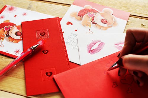 Person Holding Pen While Writing a Heart