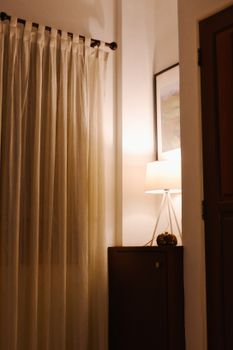 Elegant interior corner featuring warm lighting and sheer curtains for a cozy atmosphere.