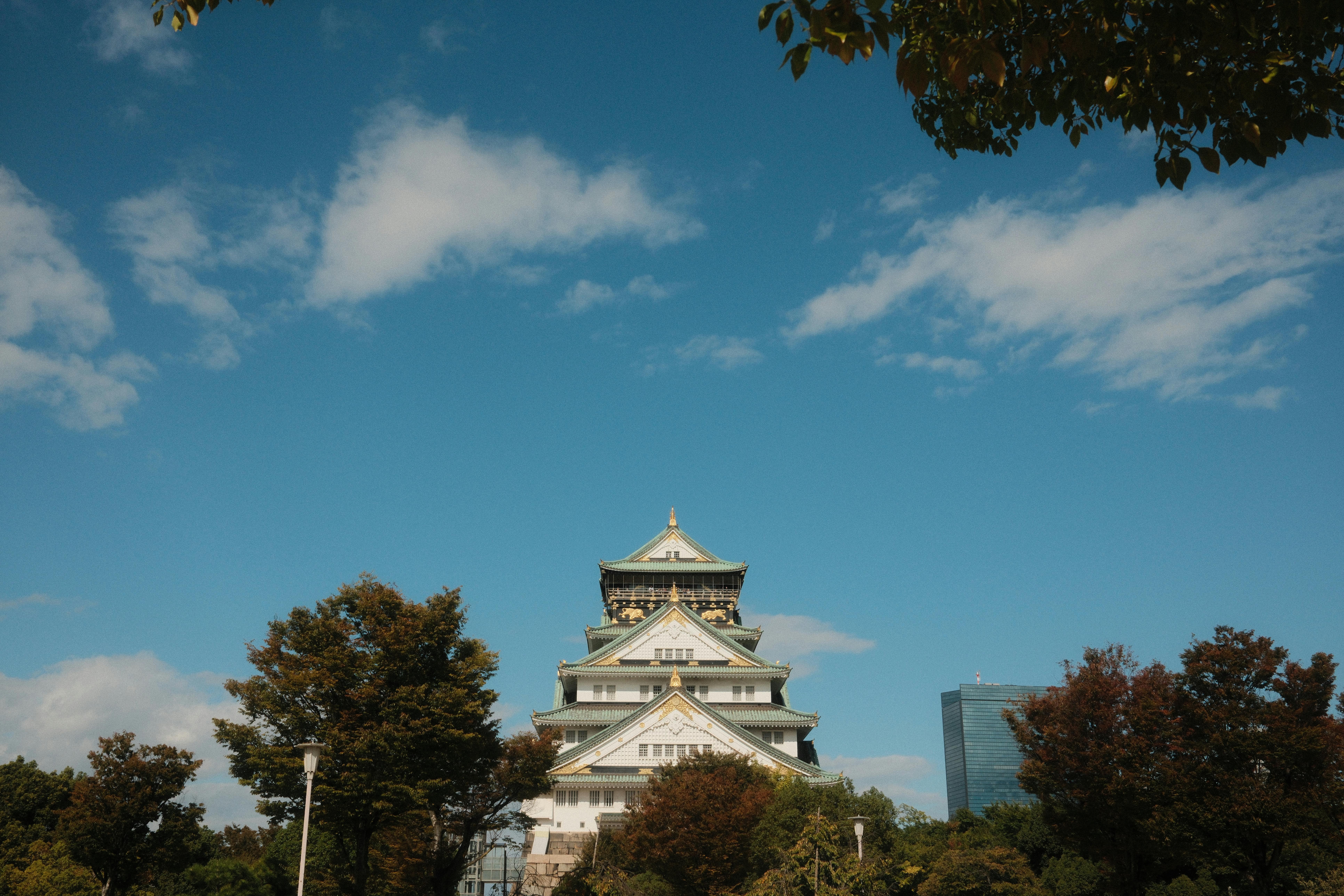 Capture of the iconic Osaka Castle surrounded by trees and a clear blue sky in Osaka, Japan.