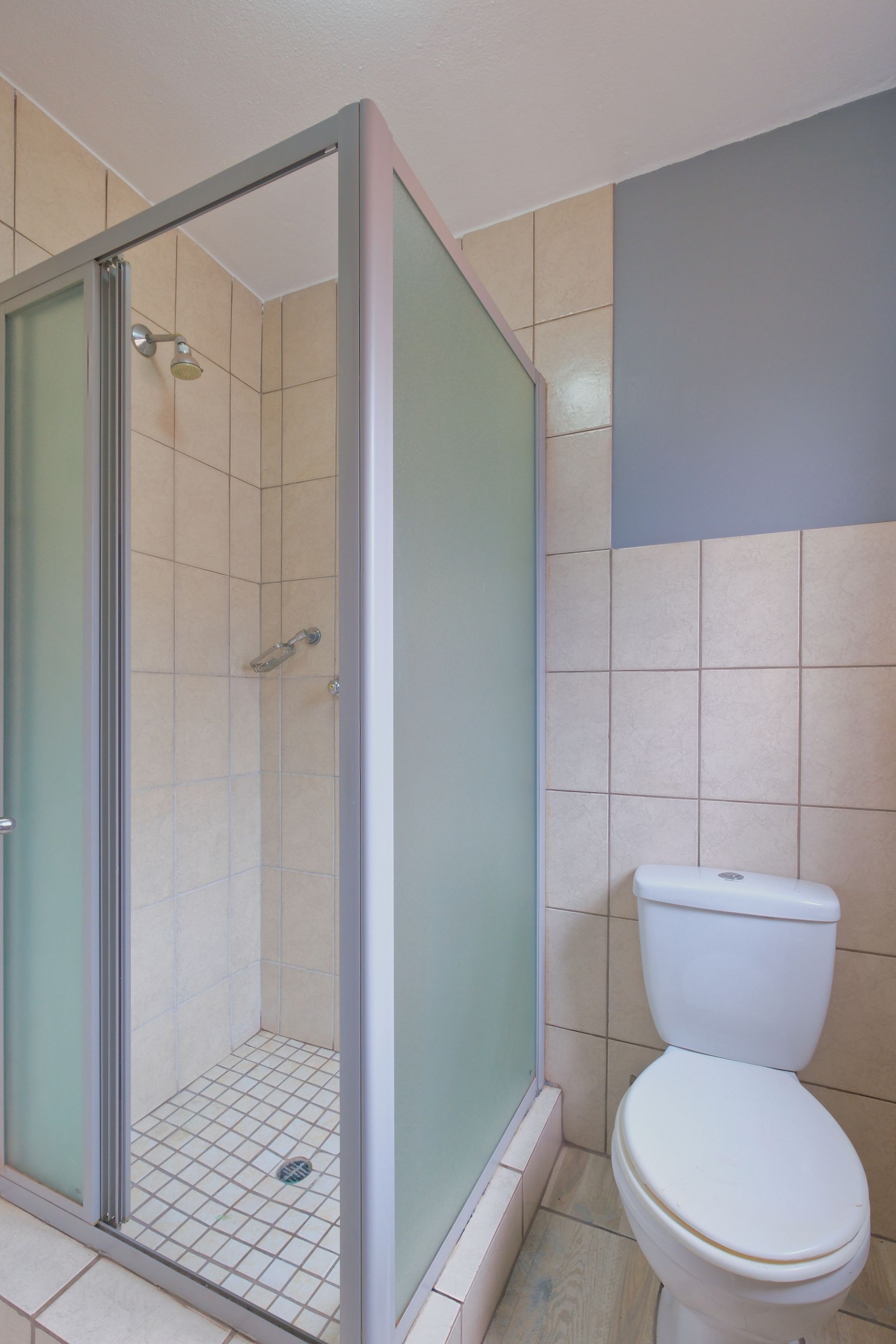 Compact tiled bathroom with shower and a clear floor path