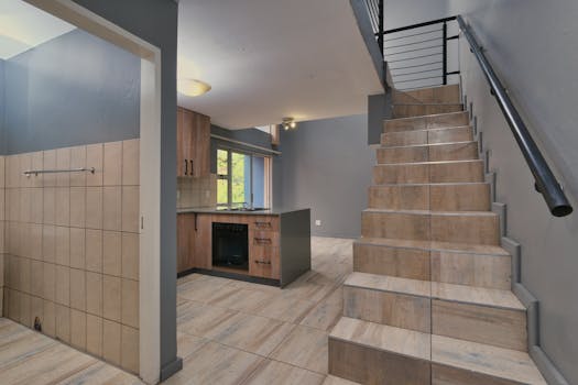 Spacious interior of a modern two-story home featuring wooden staircase and kitchen.