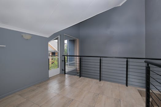 Spacious modern home interior with sleek grey walls and black metal railings, ideal for real estate listings.