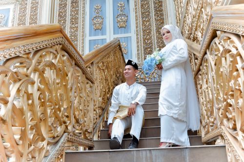 Free A couple in traditional attire posing on a decorative staircase. Perfect for wedding themes. Stock Photo