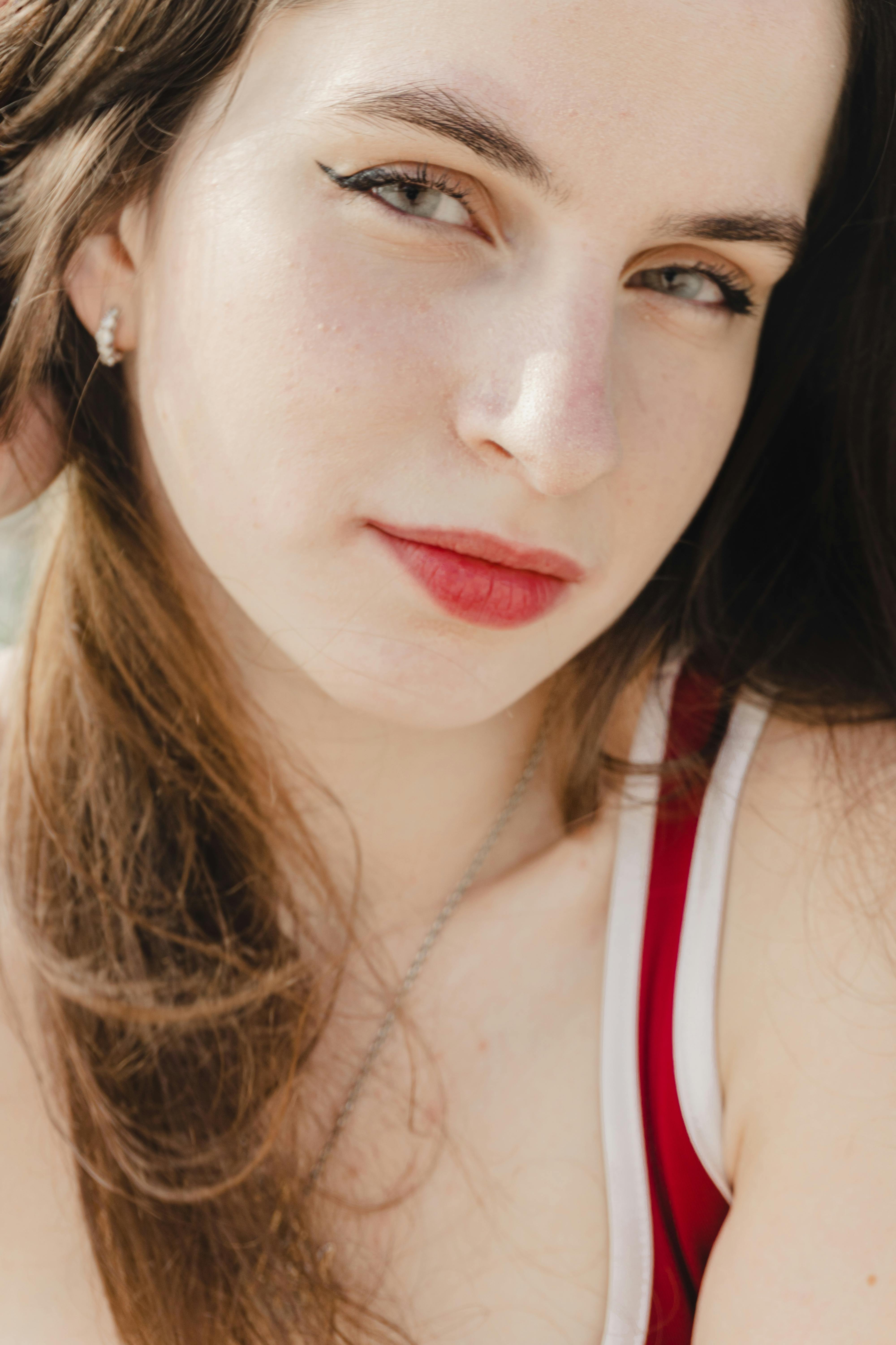 A close-up portrait of a young woman with long hair enjoying a sunny day outdoors.