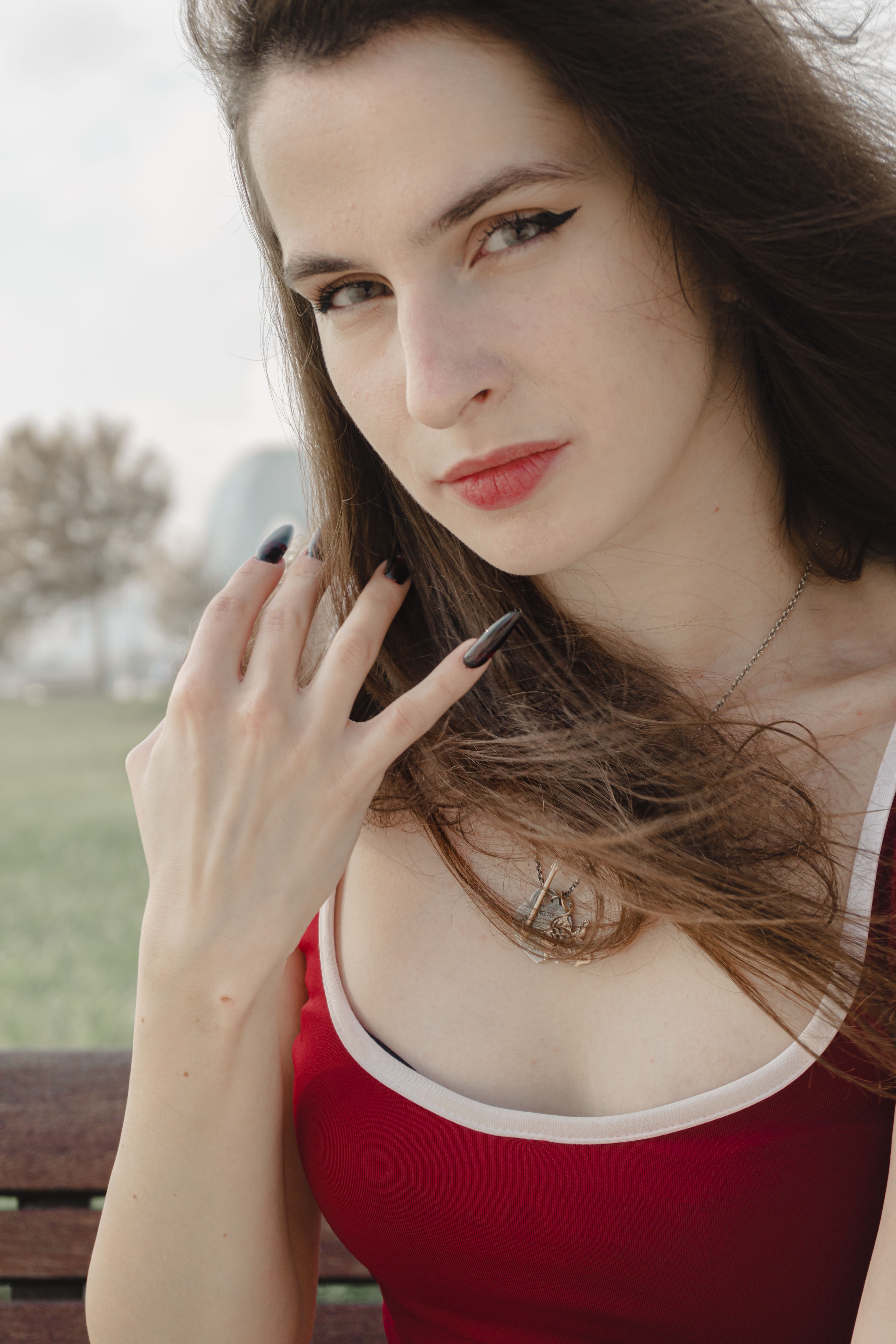Portrait of a stylish woman with long hair and red dress posing outdoors on a sunny day.