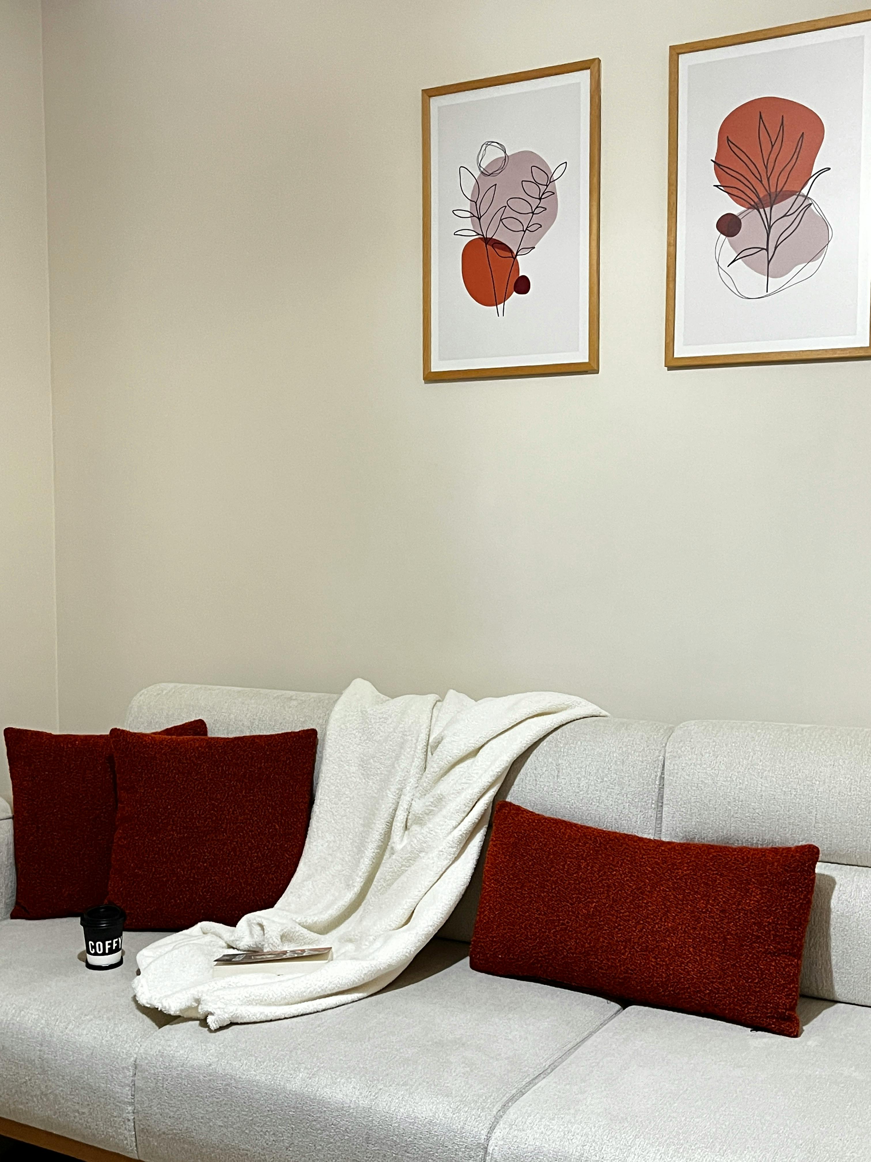 Comfortable living room with beige sofa, red cushions, and abstract art creating a warm and inviting atmosphere.