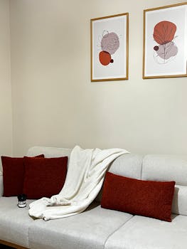 Comfortable living room with beige sofa, red cushions, and abstract art creating a warm and inviting atmosphere.