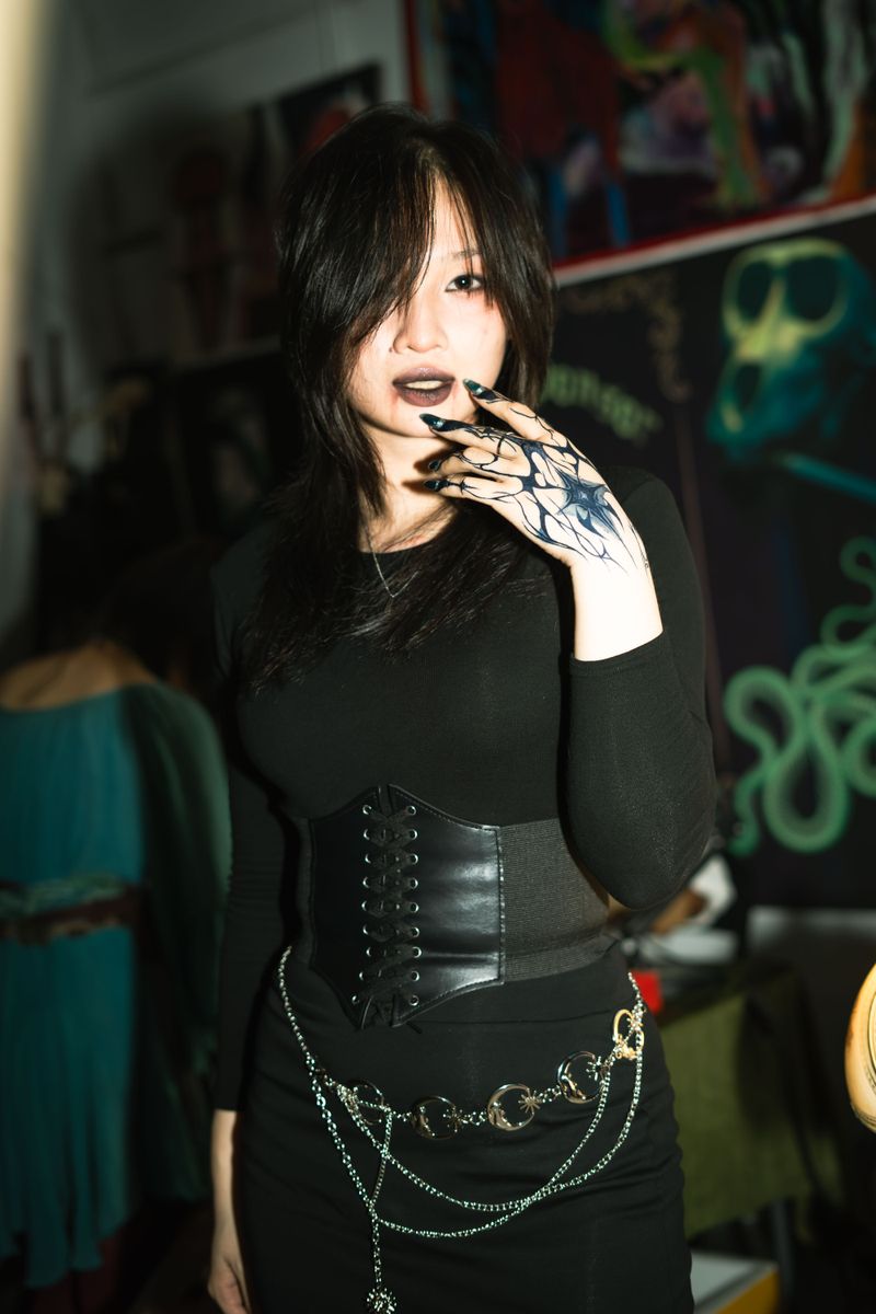 Portrait of a fashionable woman in goth style with tattooed hand and dark attire, indoors.