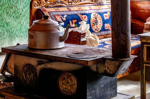 Free A cozy interior featuring a rustic stove with a metal kettle, surrounded by decorative furniture details. Stock Photo