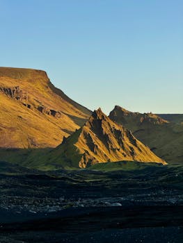 Golden sunlight casts a dramatic glow on Icelandic mountain peaks during golden hour.