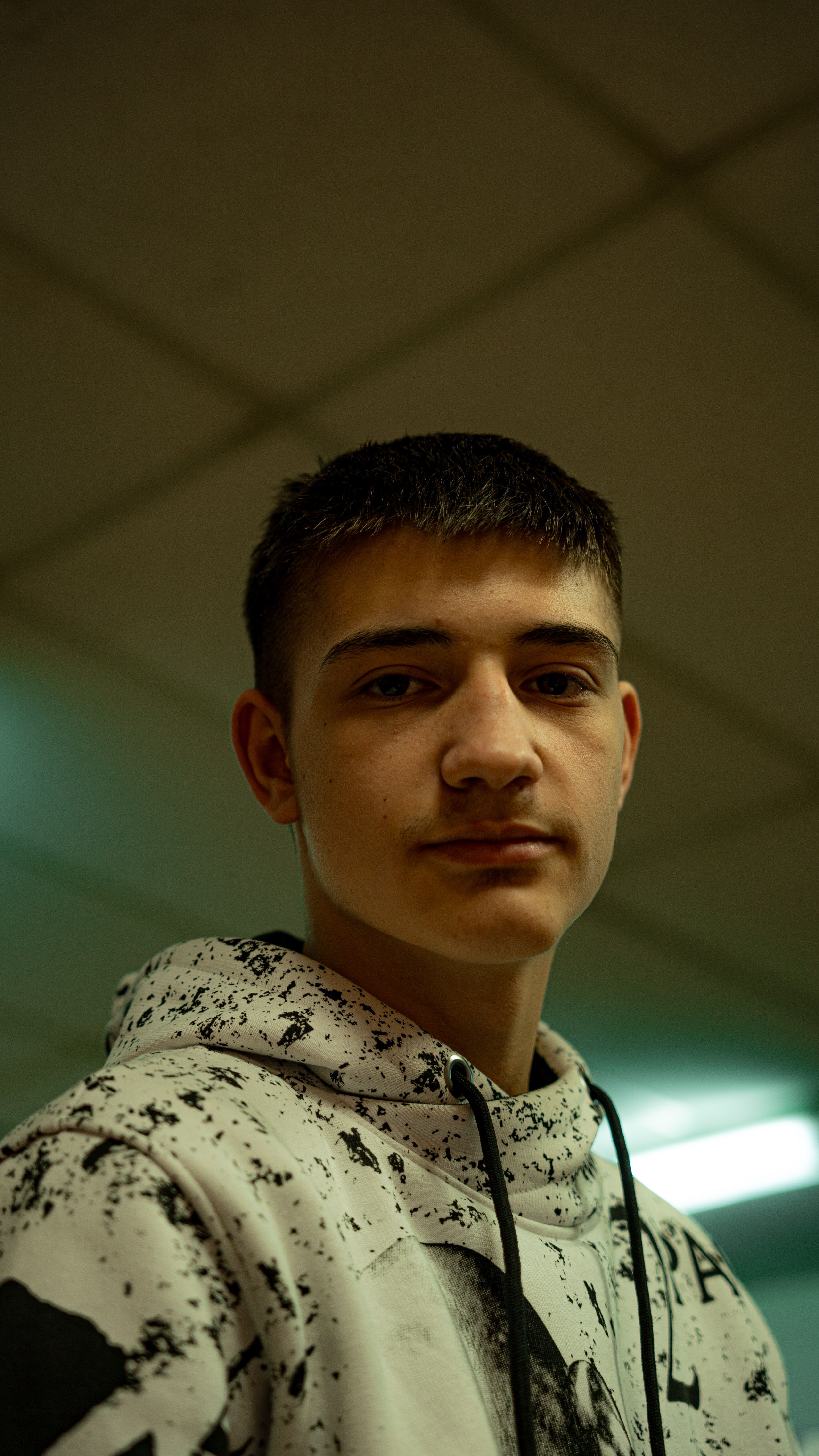 A close-up portrait of a young man in a casual hoodie indoors.