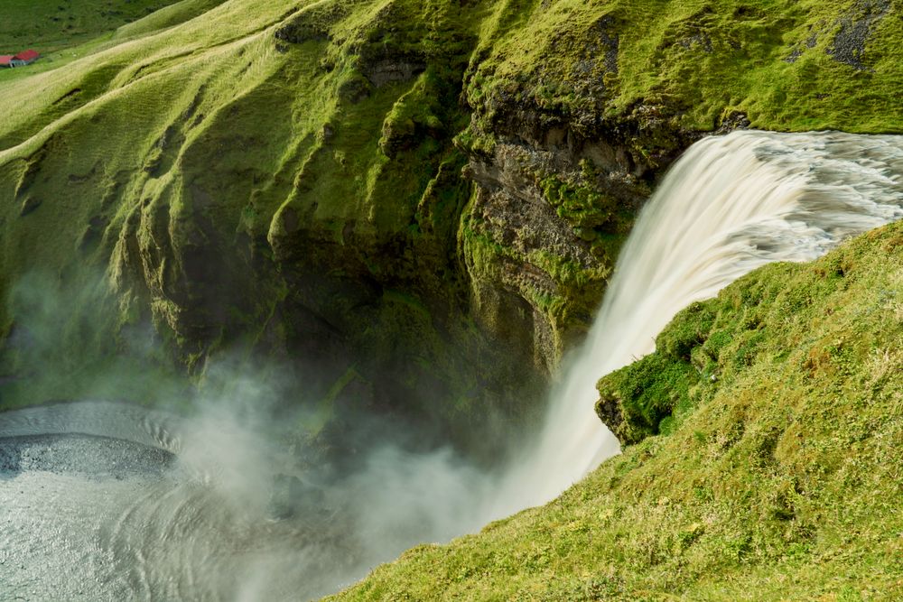 Cascada Skógafoss prăbușindu-se de pe faleza verde, pe Coasta de Sud a Islandei