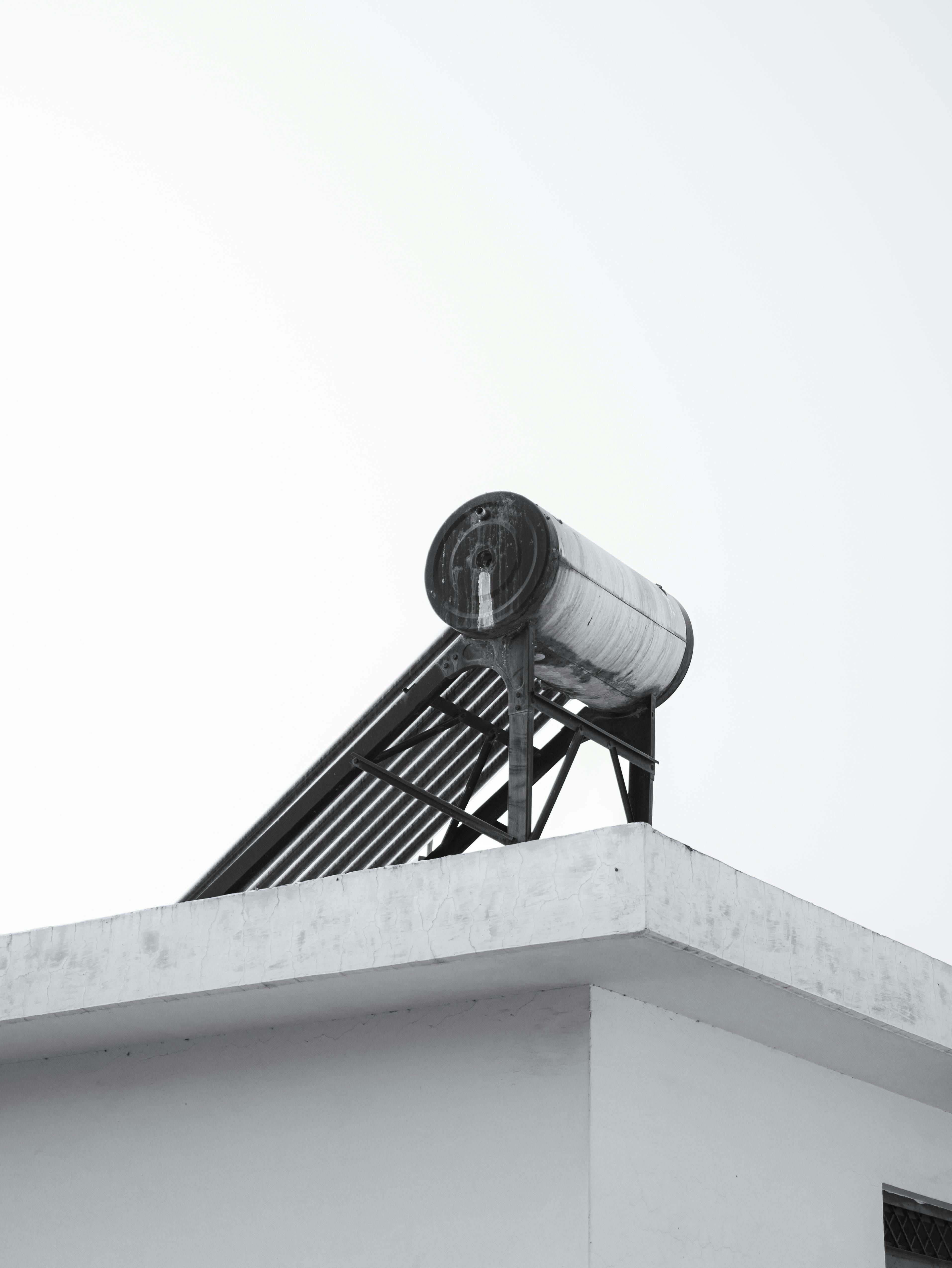 De franc Una vista minimalista d'una teulada urbana amb un escalfador d'aigua solar contra un cel clar. Foto d'estoc