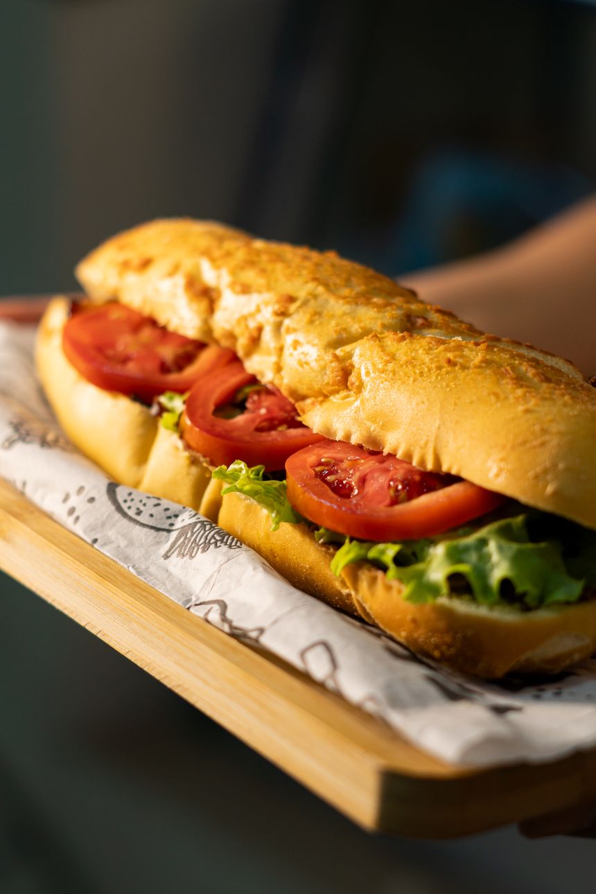 Close-up of a sub sandwich with tomato, lettuce and cheese on a wooden board, photo by ramon rangel on Pexels