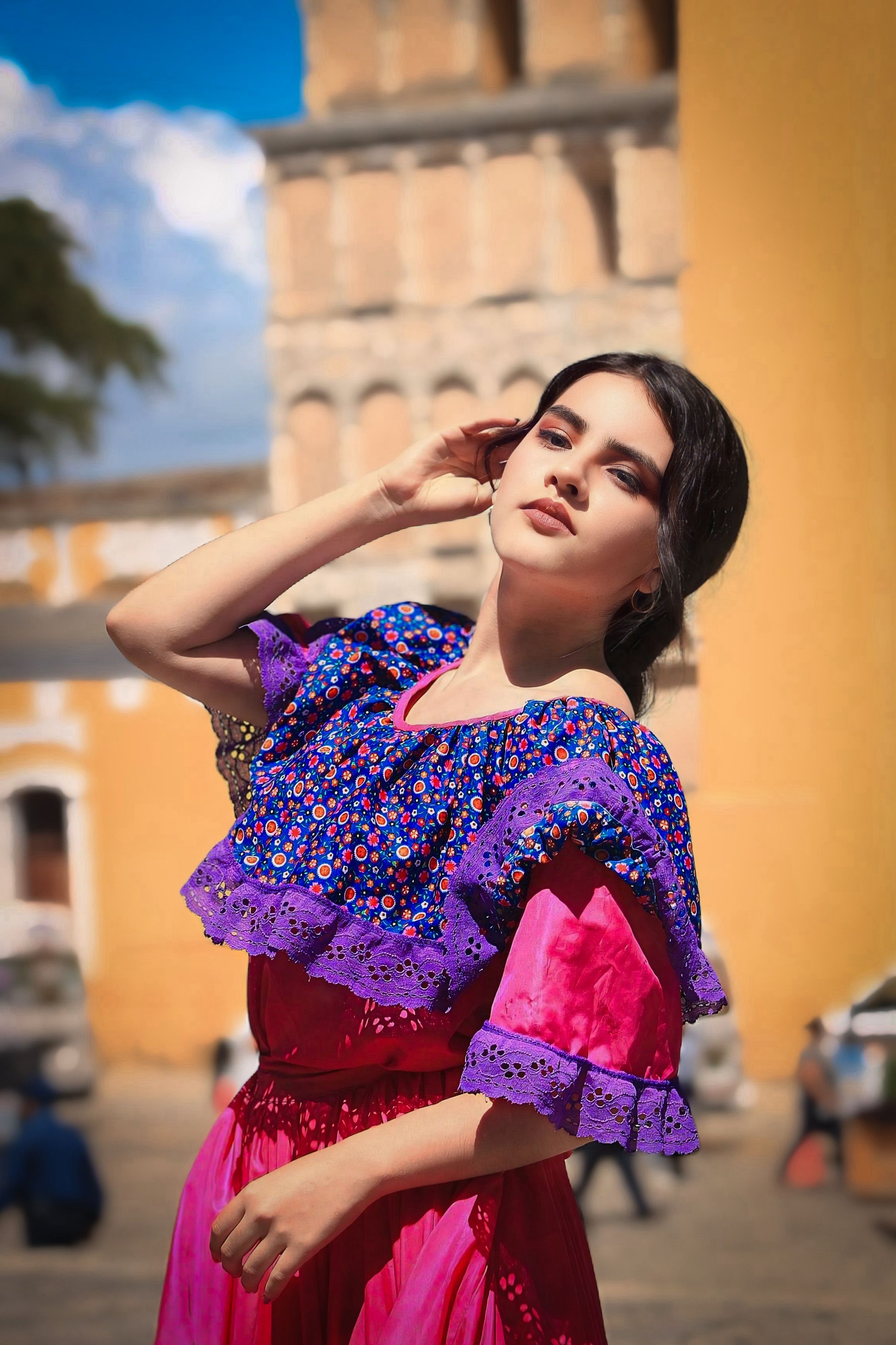 Stylish woman in vibrant traditional attire poses outdoors in Mexico.