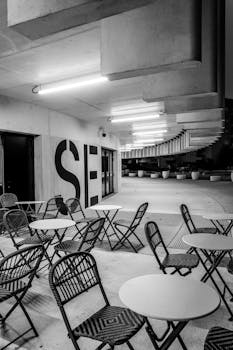 Black and white photo of an empty urban café with unique architectural design.