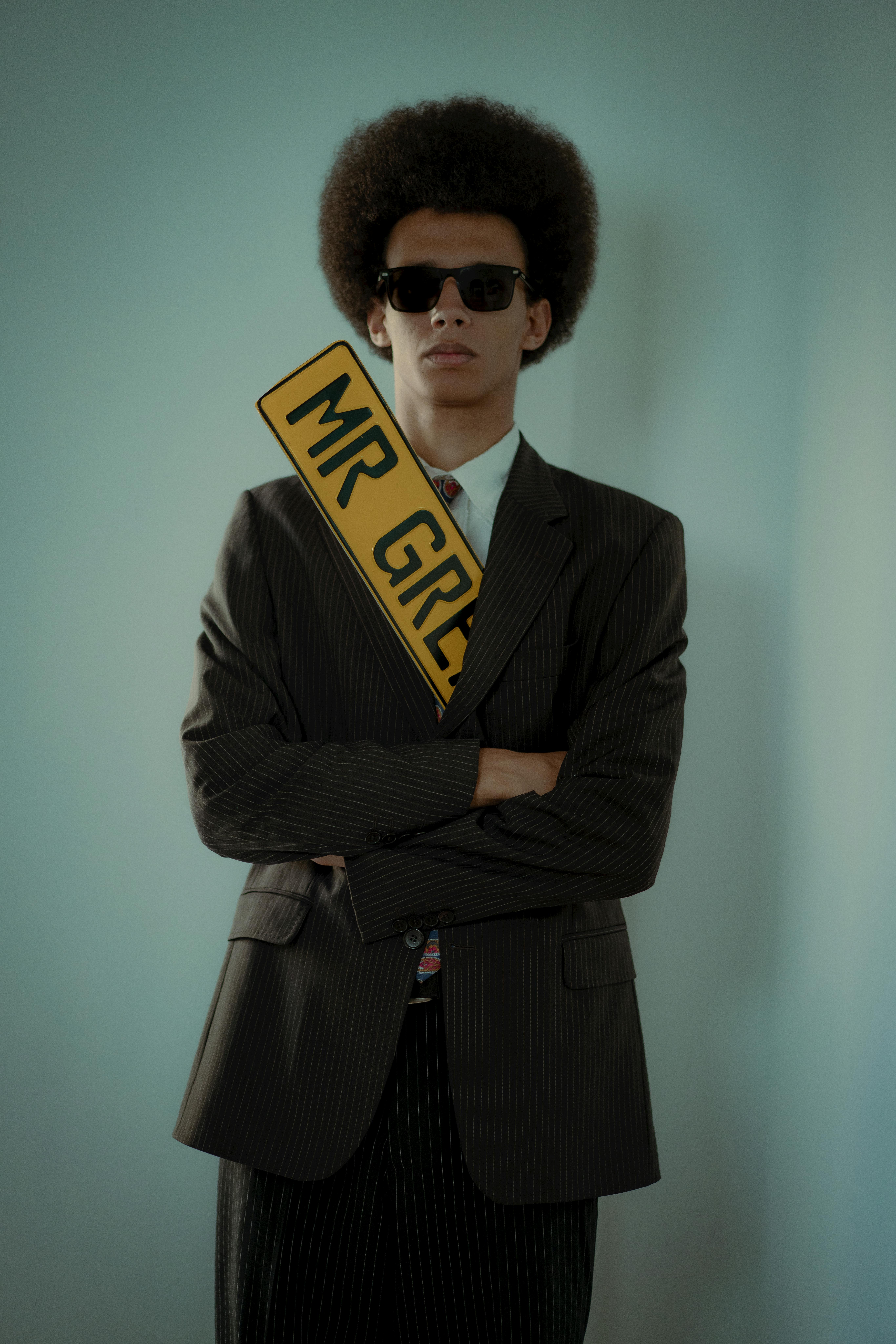 무료 정장을 입고 'MR GREY'라는 간판을 든 남자가 자신감 넘치는 표정을 짓고 있다. 스톡 사진