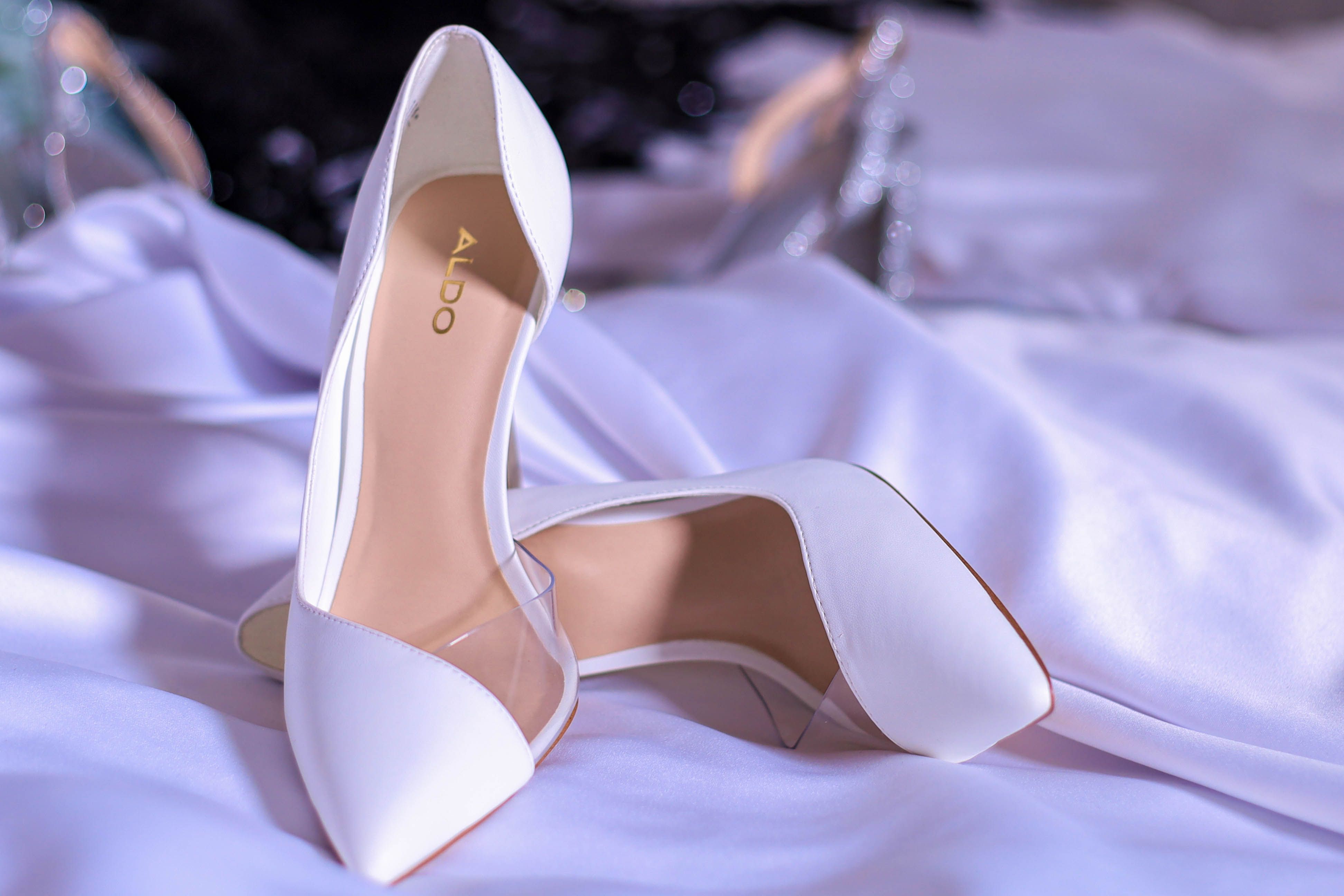 White Aldo high heels placed elegantly on satin fabric, showcasing luxury and style.