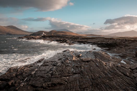 Stunning rocky coastline in Ireland with a historic lighthouse, captured at dusk with dramatic skies and waves.