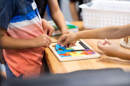 Young children learning with colorful puzzle pieces in a classroom setting.