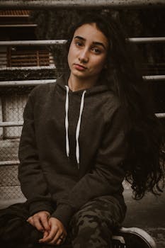 一位女士穿着连帽衫坐在户外，休闲的肖像展现了自然之美与时尚