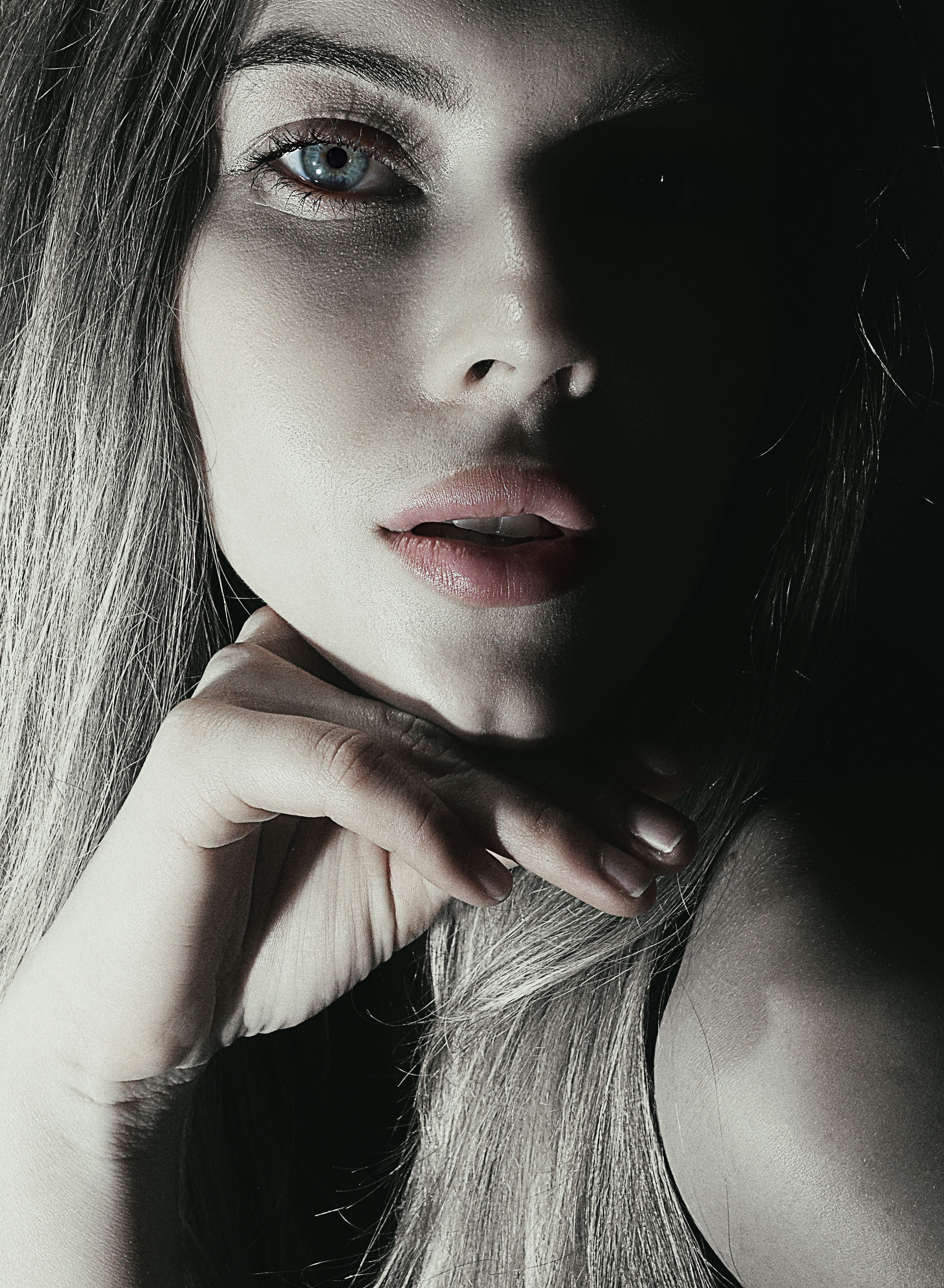 High contrast close-up portrait of a woman with dramatic lighting and focus on expression.