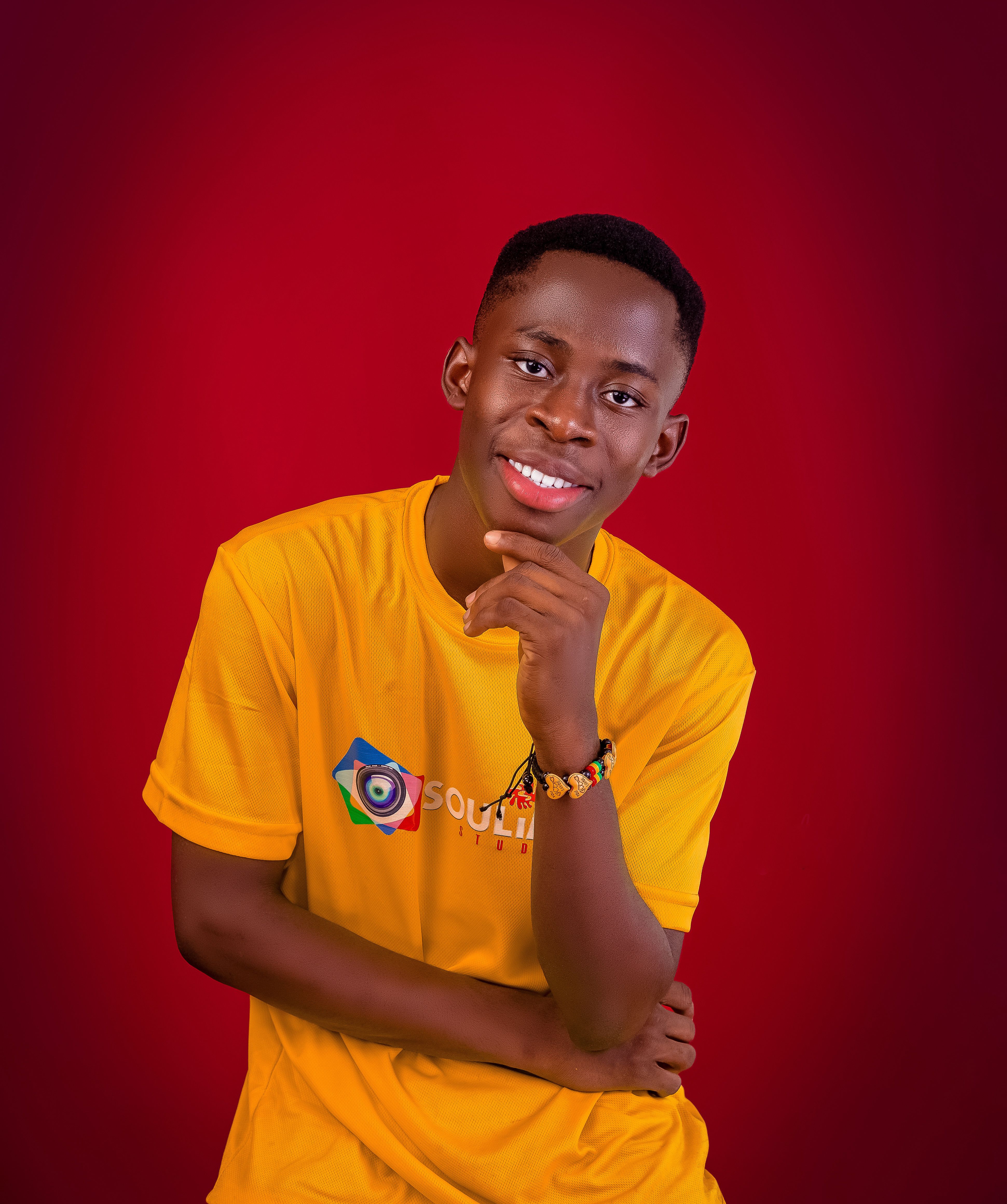 Young adult smiling confidently against a vibrant red background.