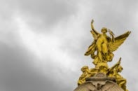 在戏剧性的灰色云层下，金色天使雕像的迷人景色象征着宏伟