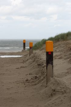 A serene sandy beach in Friesland, Netherlands, featuring coastal marker posts and sea grass.