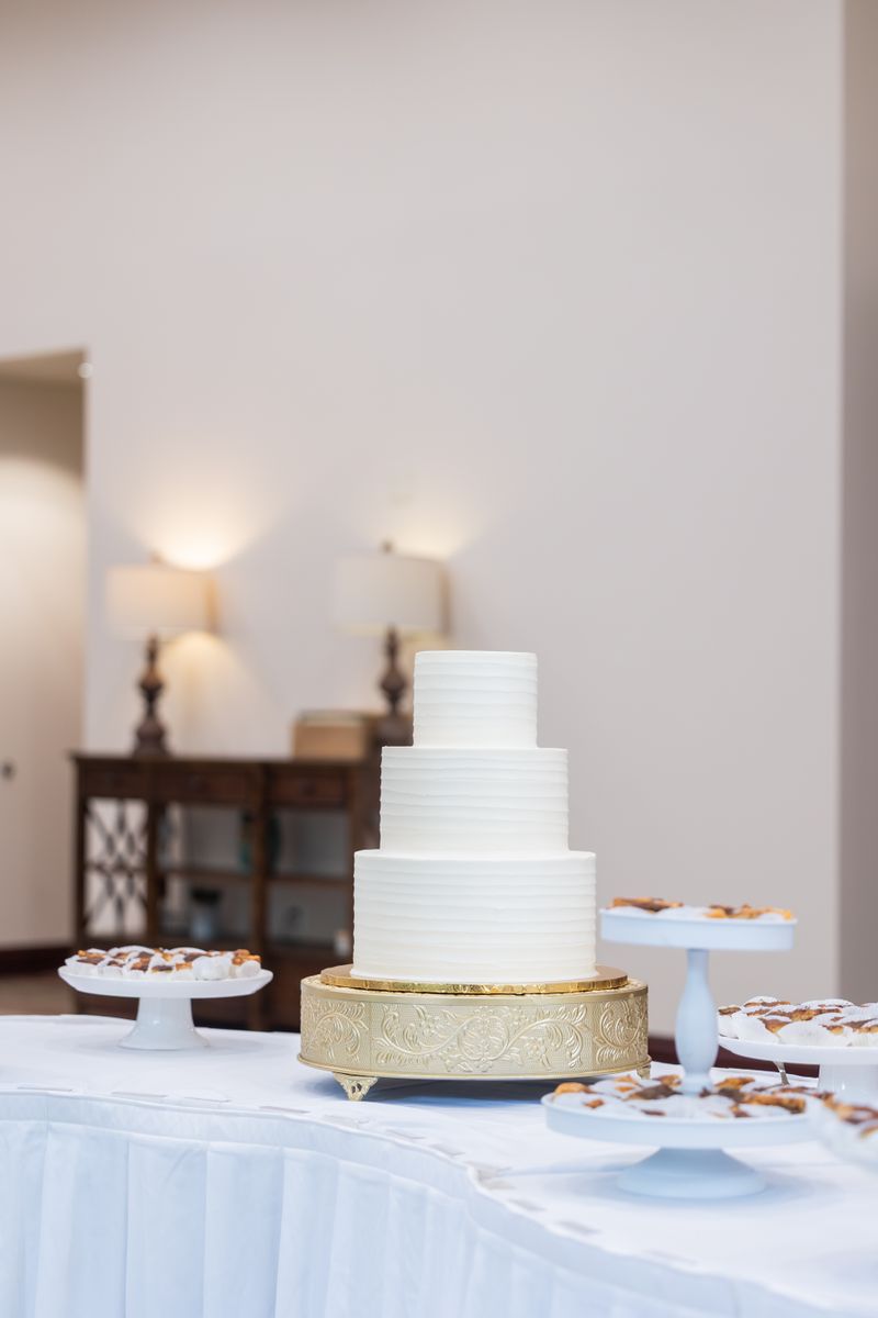 Elegant tiered white wedding cake on a gold stand