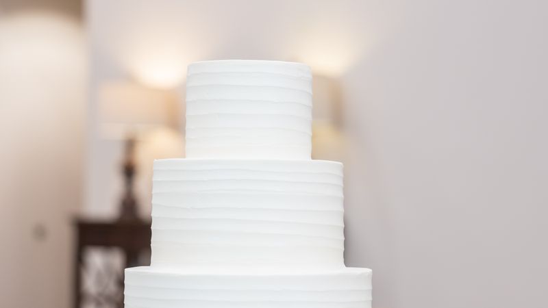 Tort de nuntă alb cu trei etaje, pe suport auriu