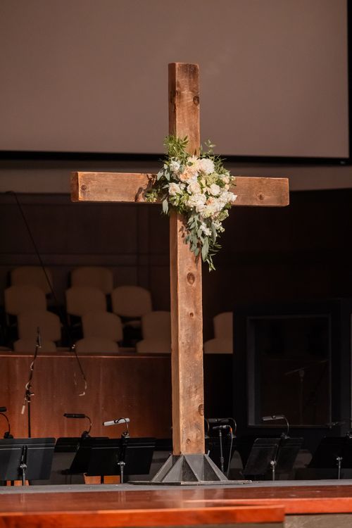 Free A wooden cross adorned with floral arrangement in a church interior, symbolizing faith. Stock Photo