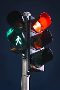 Close-up of a traffic light at night showing green pedestrian signal, with red lights glowing.