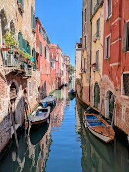 Charming Venetian canal with colorful facades and boats under the summer sun.