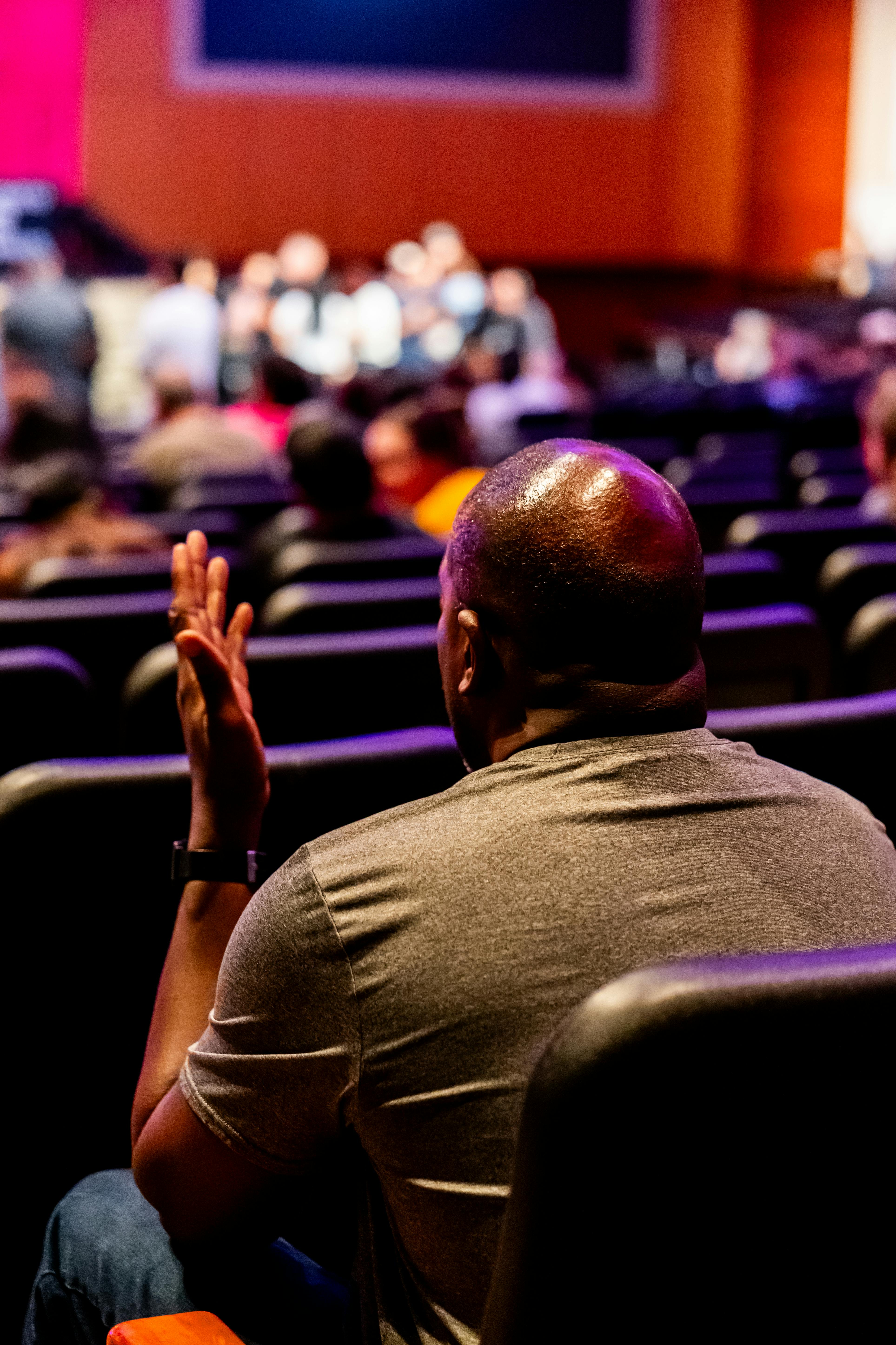 Free Man in auditorium engaged in a live presentation. Vibrant setting. Stock Photo